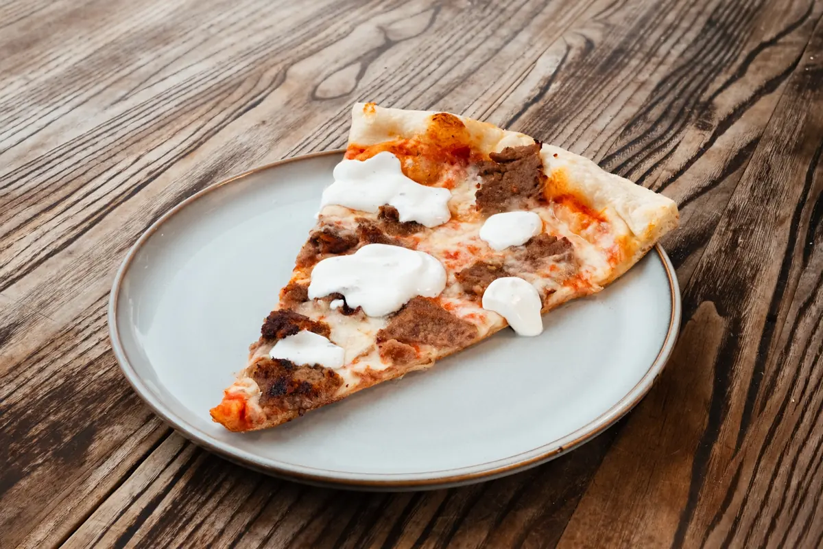 Lamb gyro pizza slice with white sauce