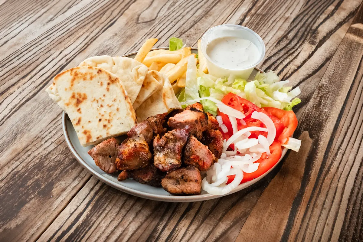 Shish kebab platter with fries, salad, pita and white sauce