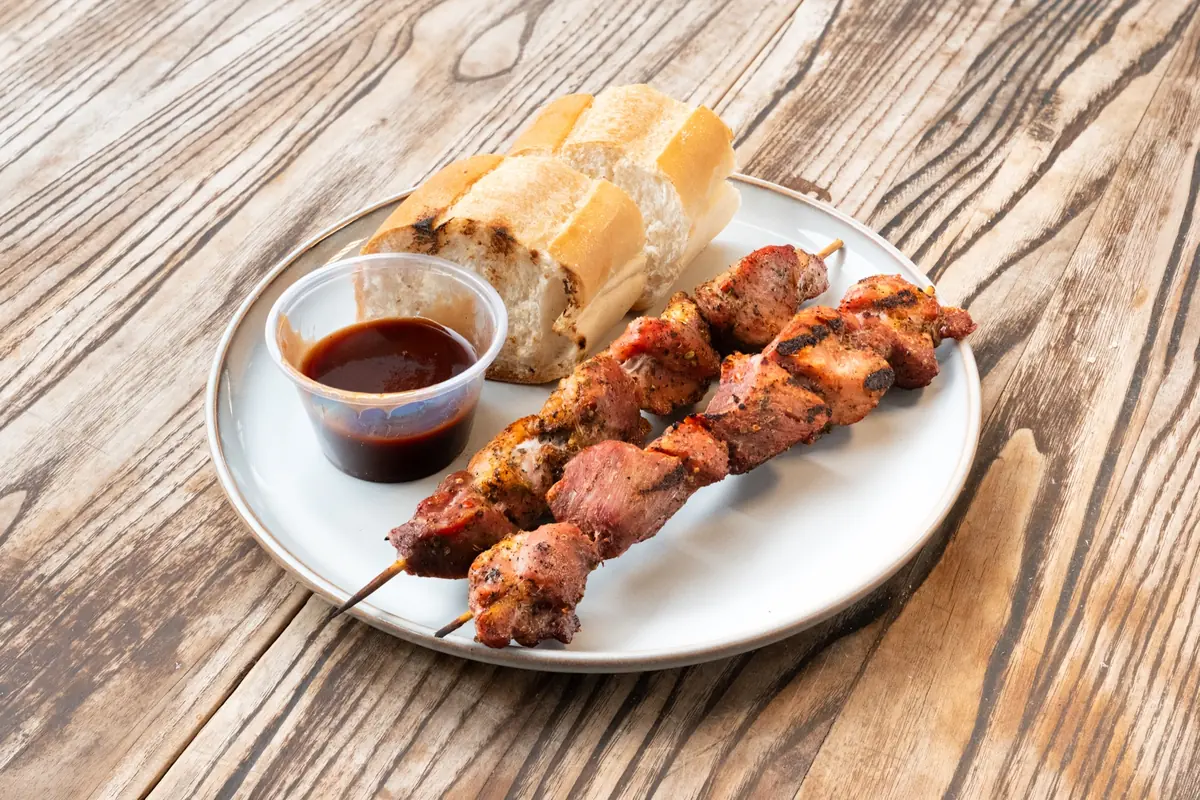Two beef shish kebab sticks with bread and sauce