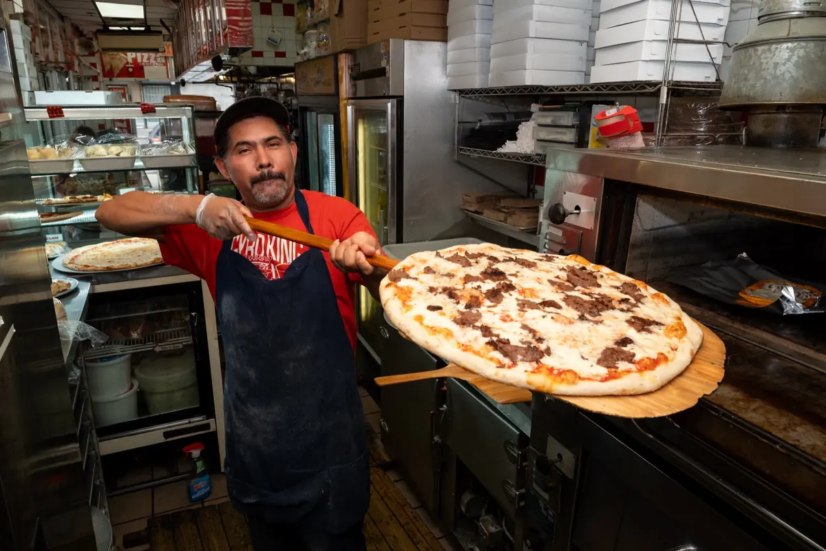 A cook holding a gyro pizza on the peel