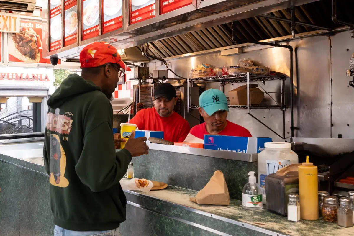 A customer ordering at the counter from the sidewalk window