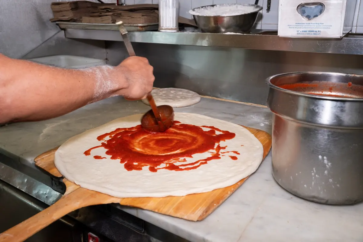Sauce spread on fresh pizza dough