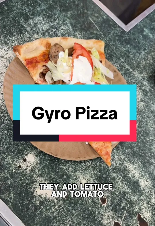 A slice of gyro pizza topped with lettuce and tomato